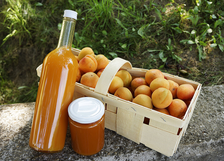 Verschiedene Marillenprodukte wie Marmelade, Mariellensaft und Marillen im Korb