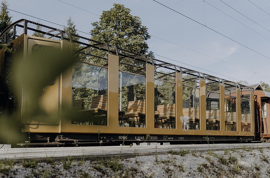 Goldener Aussichtswagen des Zuges mit verglasten Wänden und offenem Dach. 