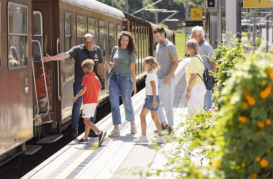 Eine Familie mit den Großeltern steigen in den Zug ein