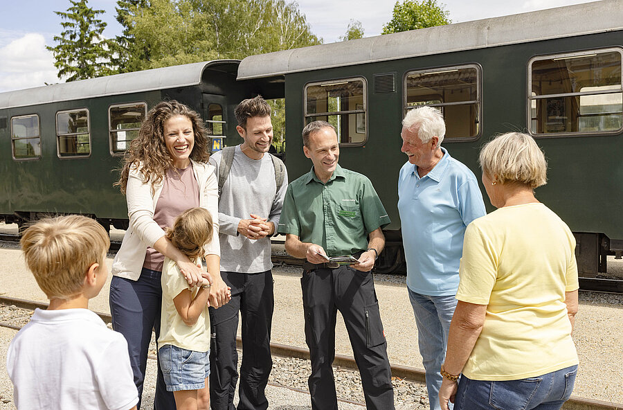 [Translate to English:] Mehrere Personen stehen am Bahnsteig vor einem Nostalgiewagon