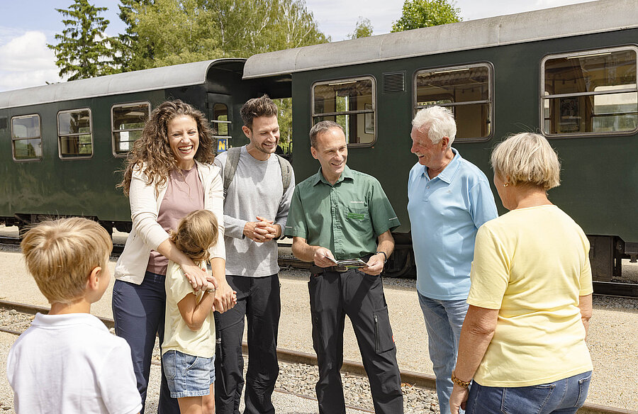 Mehrere Personen stehen am Bahnsteig vor einem Nostalgiewagon