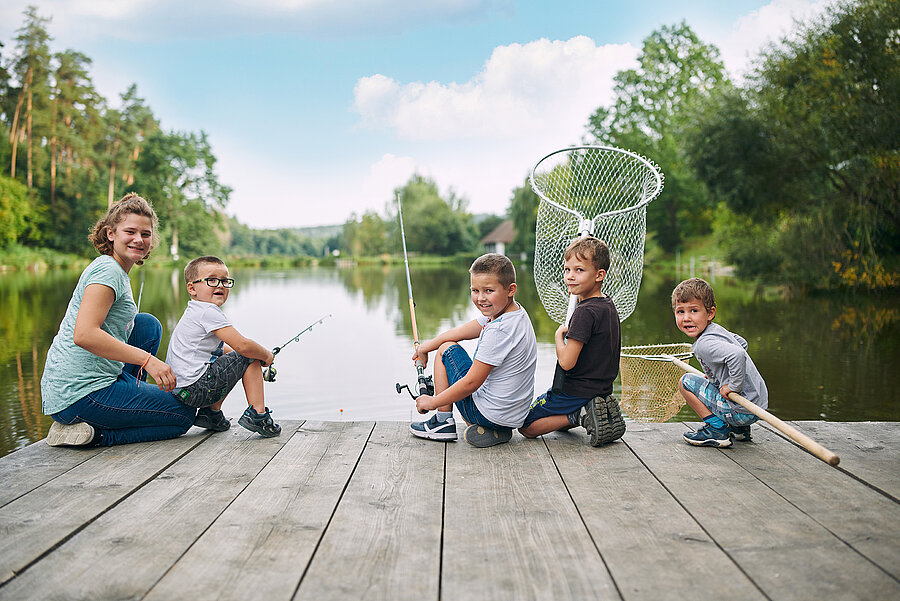 Familie beim Fischen vor Teich