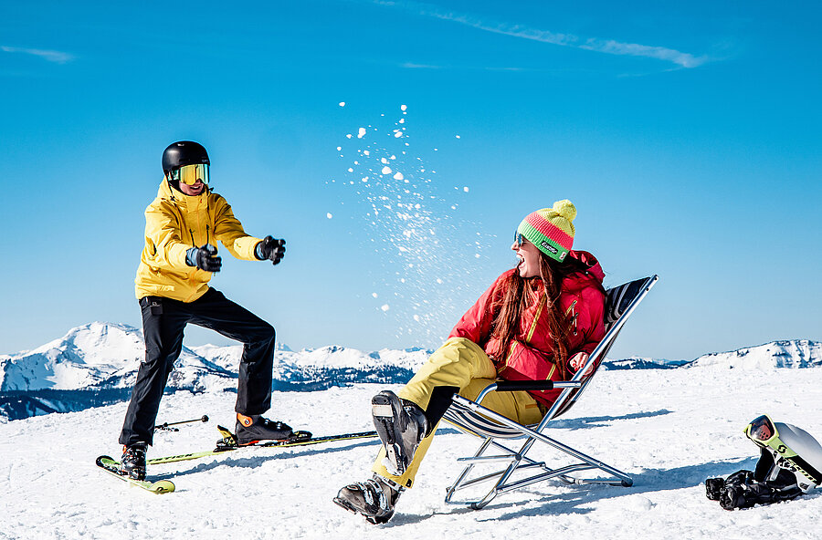 Mann auf Skiern und Frau im Liegestuhl genießen die Winterlan