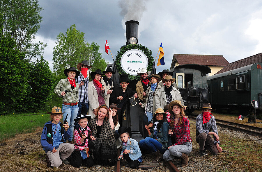 Als Cowboys verkleidete Personen vor dem Dampfzug. 