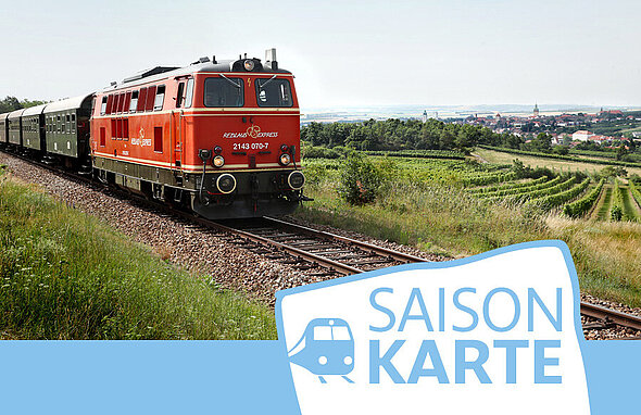 E-Lok mit Wagen fährt duch grüne Landschaft.