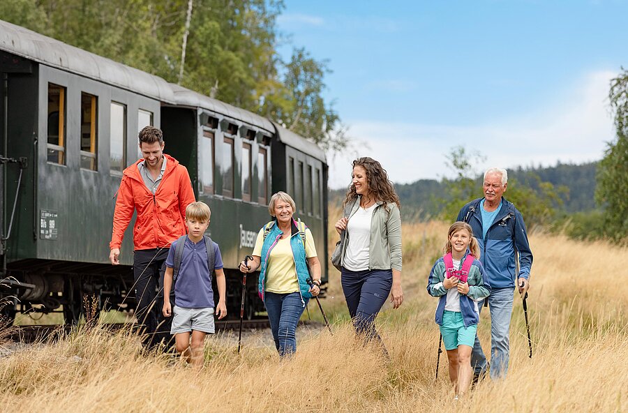 Fünfköpfige Familie auf einer Wiese neben dem Nostagliewagon