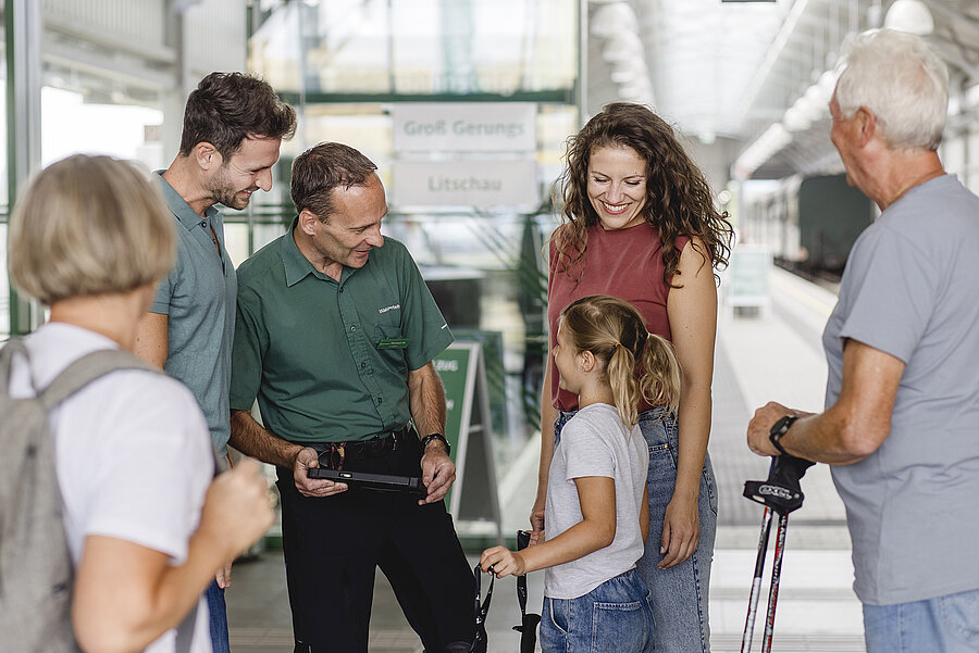 Familie und Zugbegleiter im Bahnhof Gmünd